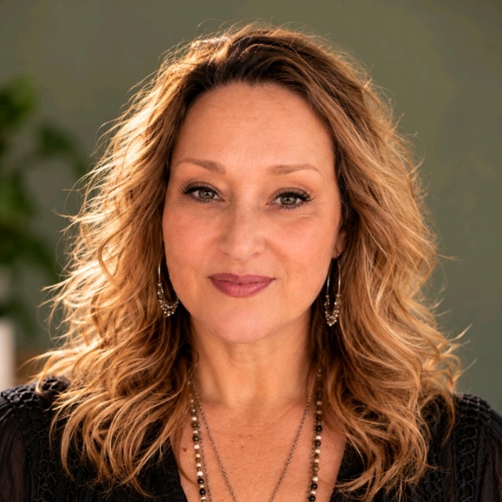 Noelle Nichols smiling, with wavy golden-brown hair and a black top